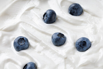 White Greek Yogurt texture. Wave of yogurt with blueberry. Ice cream background. Tasty liquid...