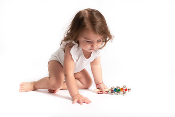 One-year-old girl is playing with a rattle on a white background