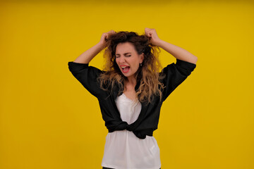 Close-up portrait of a beautiful girl on a yellow background. woman screaming and holding her hair. human emotions