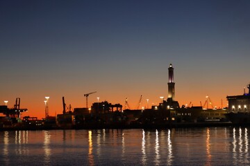 Genova, Italy- June 20,2022: Port of Porto Antico harbor with luxury  yachts and attractions, Bigo construction in historical centre of old european city Genoa with beautiful sunset reflection.