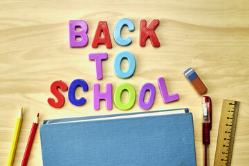 the phrase back to school is laid out in multicolored letters on the table a fountain pen a book a ruler a pencil next to the concept of education school