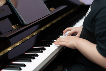 Obraz premium kid hands press piano key for music online learning