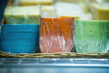 Different kinds of cheese in vacuum package. Homemade cheese, craft food. showcase decorated with straw and wood