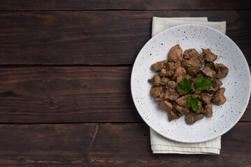 Fried or baked chicken liver with onion and sauce, green parsley leaves on a plate. Meat dish enriched with iron. copy space