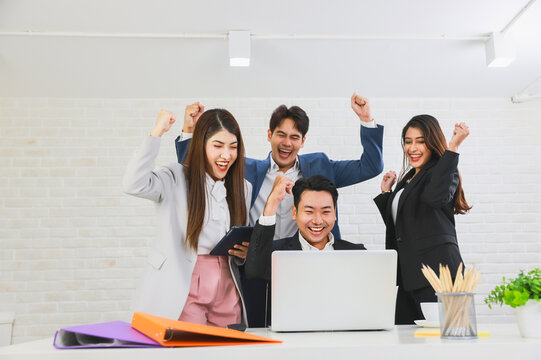 Group of young business people smiling celebrating success together in modern office, Business colleague discussing looking and doing video conference on computer