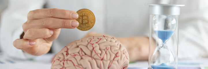 Business woman holding bitcoin coin in front of brain mockup and hourglass closeup