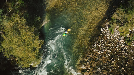 Fototapeta na wymiar Aerial kayaker over a mountain river paddling over series of whitewater rapids. Drone shot