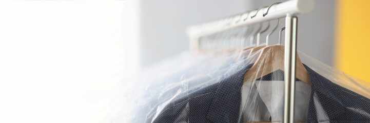 Clothes in plastic bags hanging on hanger in laundry closeup