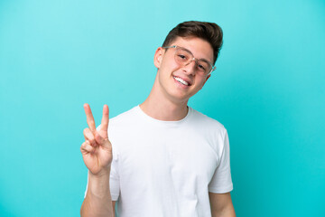 Young handsome Brazilian man isolated on blue background With glasses and doing OK sign