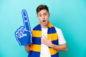Young sports fan man isolated on blue background surprised and shocked while looking right
