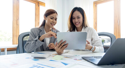 Two beautiful young asian businesswoman working together using digital tablet at office.