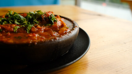 traditional georgian dish pork with vegetables in a hot ketsi pan on a wooden table background with free text space. 