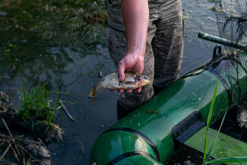 The fisherman swam to the shore on a boat and shows his catch. Overfishing damages the local...