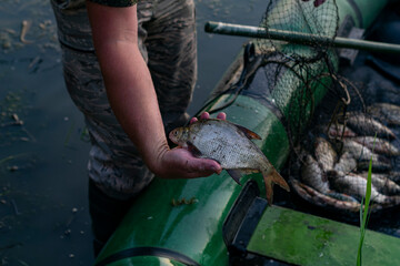 The fisherman swam to the shore on a boat and shows his catch. Overfishing damages the local...