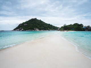 Scenic view of Koh Nang Yuan Island iconic white sand bar between crystal clear turquoise sea water with island mountain background. Near Koh Tao Island, Surat Thani, Thailand.