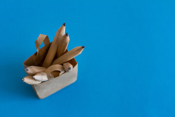 Recyclable paper bag on a Blue background with wooden pencils. School supplies. Concept of purchase of school supplies. Back to school. Education