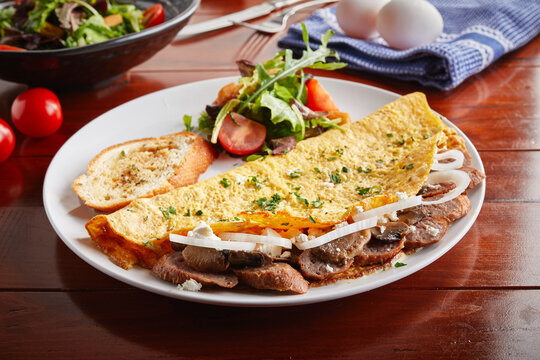 Sausage omelette roll with salad served in a dish isolated on wooden background side view