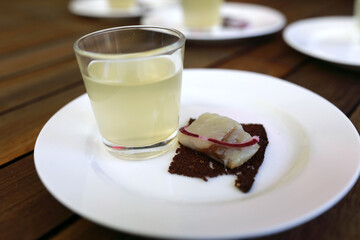 Glass of moonshine with canapes on plate