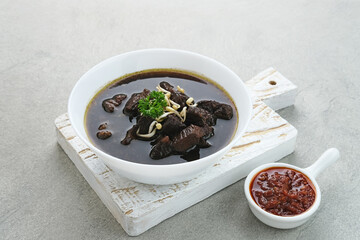 Rawon, Indonesian Traditional beef black soup. Served on a bowl with mung bean sprouts, chilli paste and salted egg
