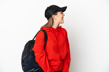 Young sport woman with sport bag isolated on white background laughing in lateral position