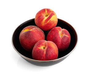 four juicy peaches in a black bowl on a white background