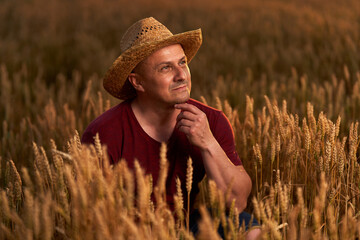 Obraz premium Farmer at sunset in the wheat field at sunset