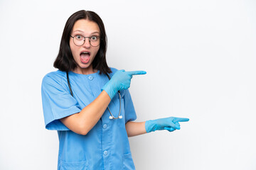 Young nurse caucasian woman isolated on white background surprised and pointing side