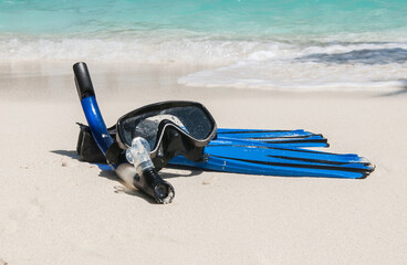 Mask and fins for scuba diving and snorkeling lie on the sandy shore against the backdrop of the...