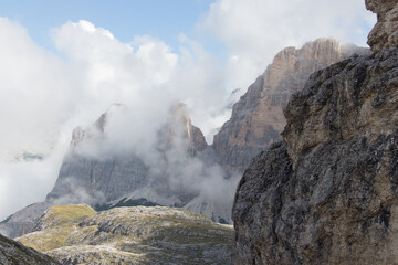 Mountain peaks seeing through clouds in a sunny day, Dolomites, Italian Alps.