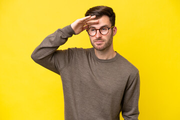 Young caucasian man isolated on yellow background looking far away with hand to look something