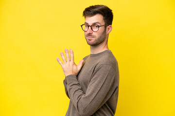 Young caucasian man isolated on yellow background scheming something