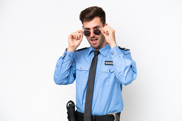 Young police caucasian man isolated on white background with glasses and surprised