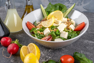 Fresh vegetable salad with feta cheese, tomatoes, lettuce walnut cucumber with salad dresssing  on wooden table