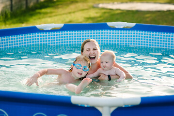 Family playing in the swimming pool. Mother and kids having fun in the pool. Summer leisure and...