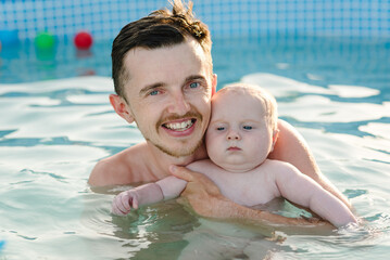 Father and baby son having fun in the swimming pool. Summer leisure and holidays and vacation...