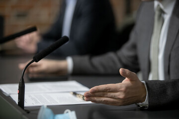 Obraz premium Close Up Executive Lawyer or JUDGE HAND Striking the GAVEL on Sounding Block in LAW OFFICE, JUSTICE and LAW Concept Background, Businessmen in Suits sitting on the table Next to a ็ammer.