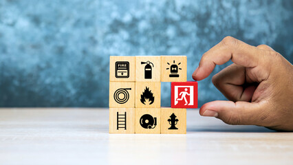 Hand choose wooden block stack with door exit sing or fire escape and fire prevent icon with fire extinguisher and emergency protection symbol for safety and rescue in the building.