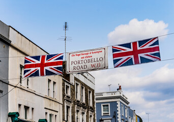 Hanging street sign pointing the beginning of "Portobello Road" with British flags, in Notting Hill, Portobello Road, London, United Kingdom