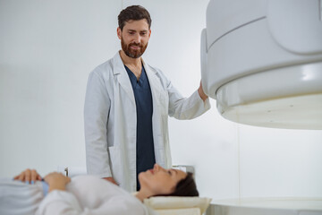 Radiologist controls MRI or CT or PET Scan with female patient undergoing procedure