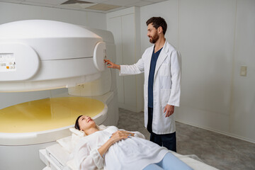 Radiologist controls MRI or CT or PET Scan with female patient undergoing procedure