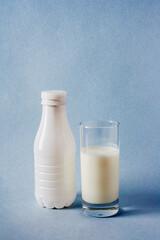 a bottle and a glass of yogurt on a blue background, a copy of the space