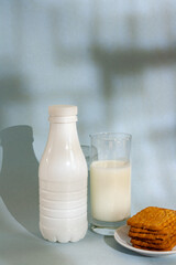 a bottle, a glass of yogurt, cookies with a shadow on a blue background, a healthy snack