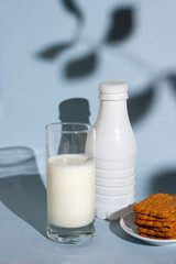 bottle, glass with yogurt, cookies on a blue background, shade from a tree, morning breakfast