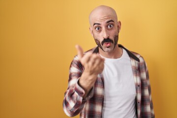 Hispanic man with beard standing over yellow background looking at the camera blowing a kiss with hand on air being lovely and sexy. love expression.