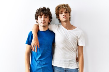 Fototapeta premium Young gay couple standing together over isolated background relaxed with serious expression on face. simple and natural looking at the camera.