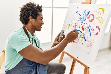 Young african american artist man using smartphone to draw at art studio.