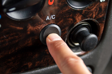 Close-up of an air conditioning button pressed by a man inside a car