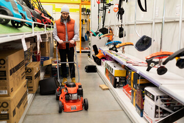 Fototapeta premium man picking up a new lawn mower for his lawn at a hardware store