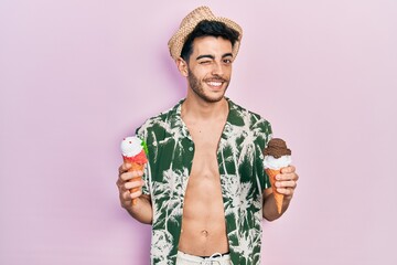 Young hispanic man wearing summer style holding ice cream winking looking at the camera with sexy...