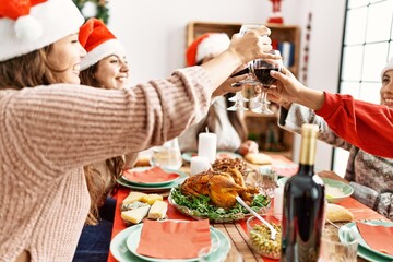 Group of young hispanic women smiling happy having christmas dinner and toasting with wine at home.